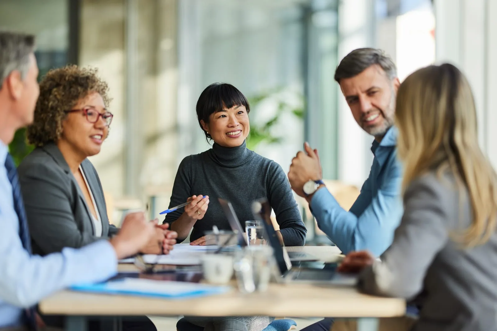 A diverse team of professionals in a friendly working meeting in a bright, modern office.